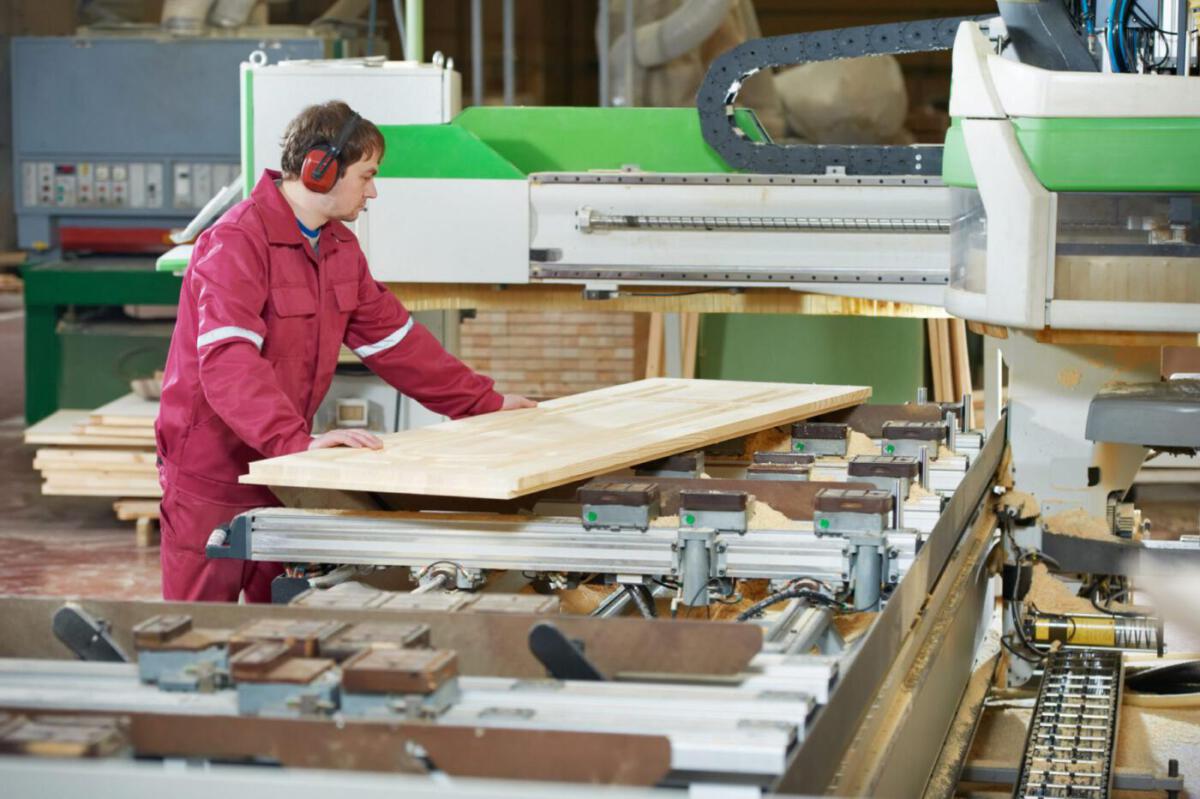 Closeup process of carpenter worker with circular saw machine at wood beam cross cutting during furniture manufacture